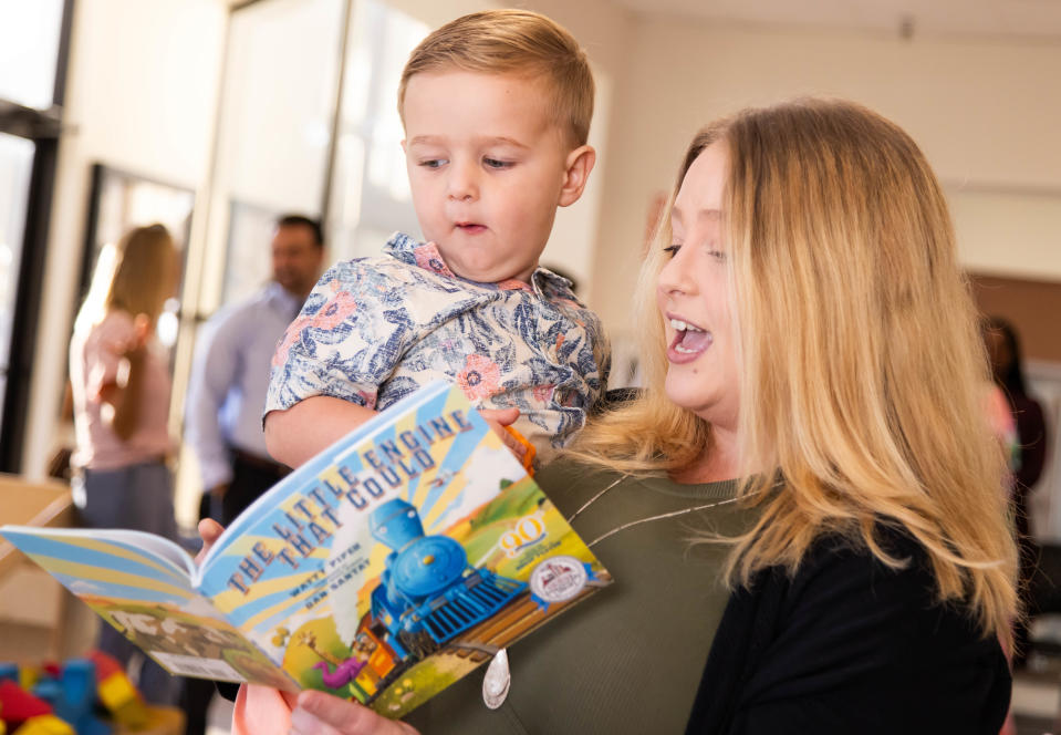 Waylon Piechowiak, 2, left, listens as his mother Elizabeth Ekleberry, right, reads him “The Little Engine That Could” as about 50 people attended the ribbon cutting for the Dolly Parton’s Imagination Library at the Early Learning Coalition of Marion County (ELCMC) Thursday morning April 25, 2024. Waylon was the first child to sign up for Dolly Parton’s Imagination Library.