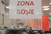 A patient lies on a bed in the emergency room, turned into a CODIV-19 unit due the high number of cases, at the Bagdasar-Arseni hospital in Bucharest, Romania, Tuesday, Oct. 12, 2021. Romania reported on Tuesday nearly 17,000 new COVID-19 infections and 442 deaths, the highest number of coronavirus infections and deaths in a day since the pandemic started, as the nation's health care system struggles to cope with an acute surge of new cases. Door sign reads "Red Zone".(AP Photo/Andreea Alexandru)