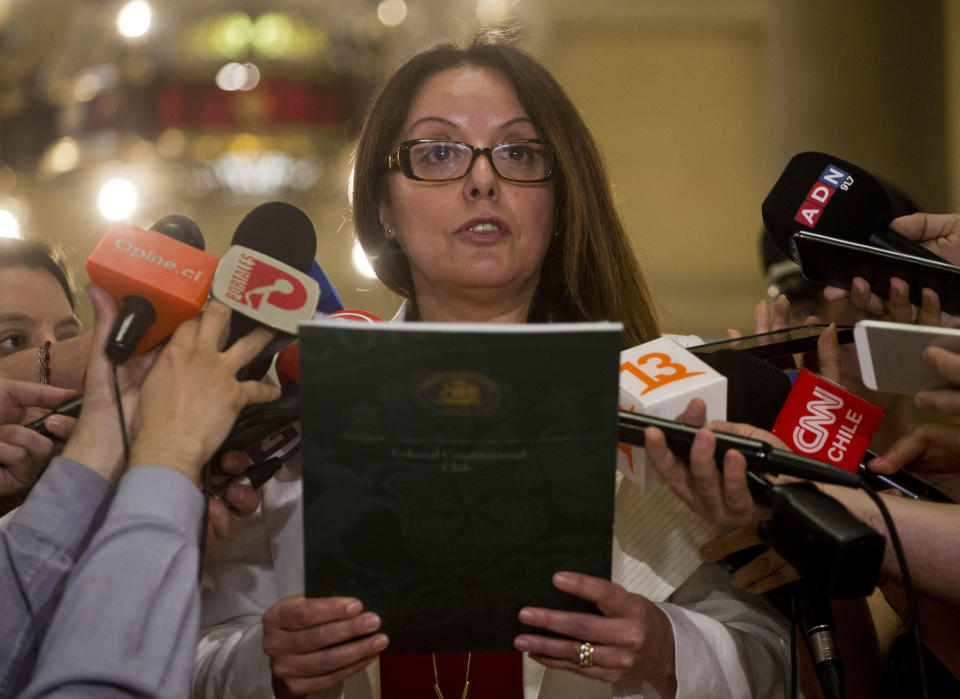 Reporters surround Monica Sanchez, as she reads Chile’s Constitutional Court ruling on human rights violators, in Santiago, Chile, Thursday, Dec. 27, 2018. The ruling is a defeat for conservative forces in Chile’s ruling party which had asked the court to declare as unconstitutional the requirements recently approved by the center-left opposition in Congress. The Court upheld measures tightening the requirements for human rights violators to get parole, including that they have completed two thirds of their sentence. (AP Photo/Esteban Felix)