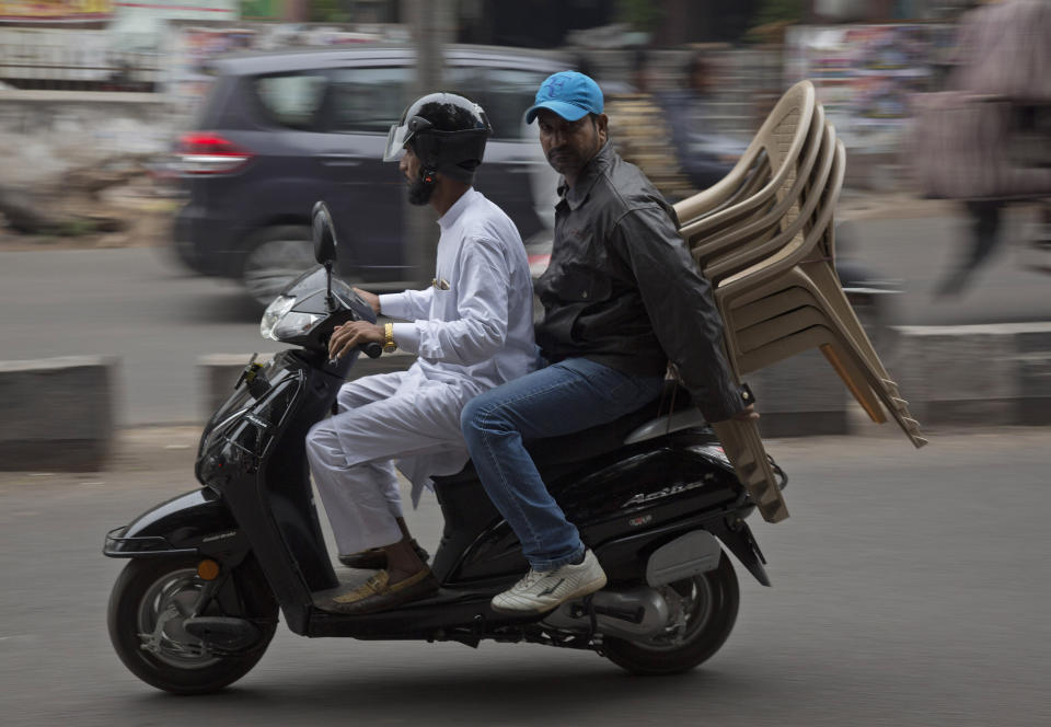 In this Dec. 17, 2018, photo, two men transport chairs purchased from a shop at the Nampally furniture market in Hyderabad, India. Such furniture markets, where customers haggle over prices and work with carpenters to design made-to-order housewares, is the competition Swedish giant Ikea faces in tackling the $40 billion Indian market for home furnishings, which is growing quickly along with the country’s consumer class. Ikea declined to break out India revenues, but Forrester Researcher analyst Satish Meena said that within five years the company hopes to capture $4 billion annually _ or 10 percent of India’s furniture and home goods market. (AP Photo/Mahesh Kumar A.)