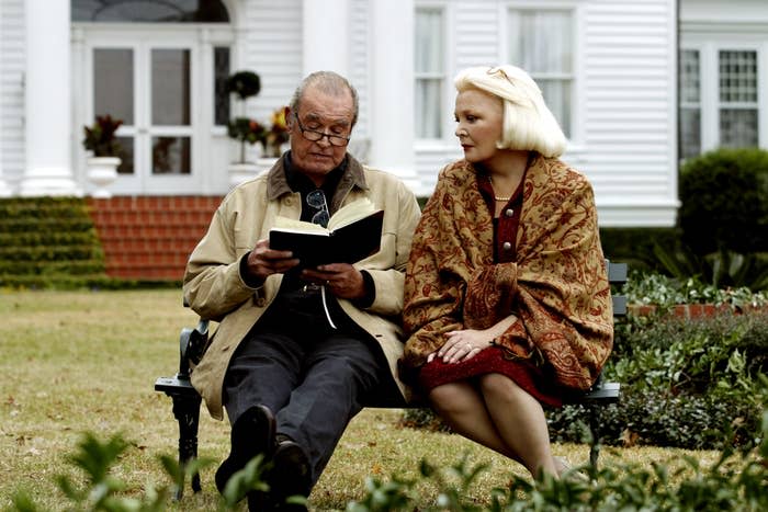 James Garner reading a book to Gena Rowlands sitting on a bench in a scene from "The Notebook"