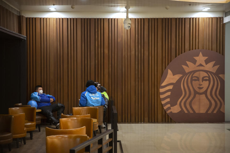 In this Tuesday, Jan. 28, 2020 photo, delivery drivers wear face masks as they wait for orders at a Starbucks cafe in Beijing. Fears of a virus outbreak have kept many indoors and at home in China's capital. Cultural landmarks such as the Great Wall and Forbidden City have closed their doors to visitors, nearly deserted shopping malls have reduced their operating hours, and restaurants that remain open draw just a handful of customers. (AP Photo/Mark Schiefelbein)