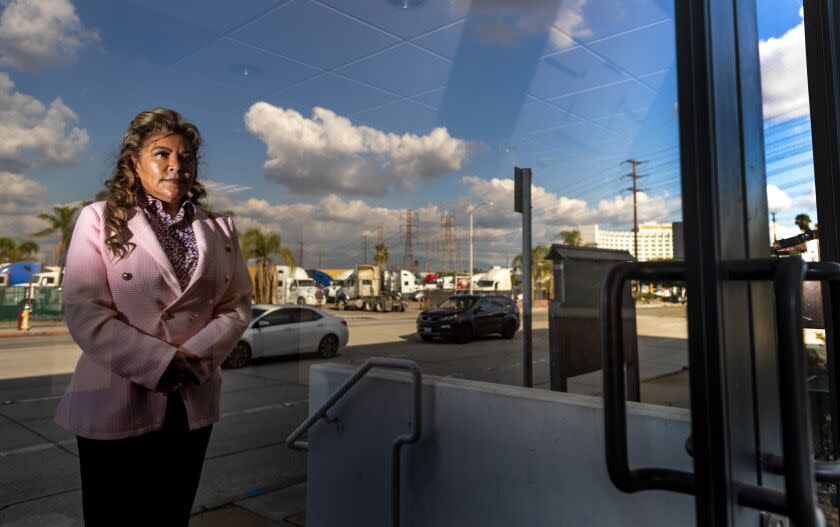 COMMERCE, CA - DECEMBER 7, 2022: Board member Leticia Vasquez is reflected in the front doors of the old Central Basin Municipal Water District building off Telegraph Road on December 7, 2022 in Commerce, California. Vasquez has vehemently criticized General Manager Alex Rojas, pointing out that he was charged in August with money laundering, soliciting a bribe and grand theft by embezzlement. She is demanding the board consider additional measures to safeguard its finances against potential fraud.(Gina Ferazzi / Los Angeles Times)