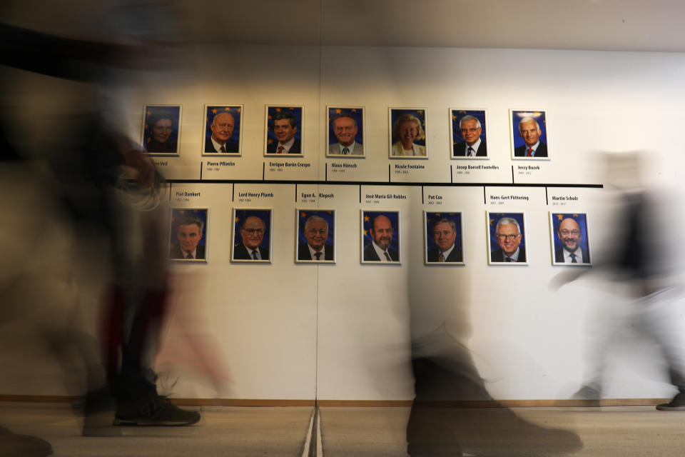 People walk past portraits of former European Parliament Presidents in the corridor of the European Parliament in Brussels, Monday, May 27, 2019. Europeans woke Monday to a new political reality after European Parliament elections ended the domination of the EU's main center-right and center-left parties and revealed a changed political landscape where the far-right, pro-business groups and environmentalists will be forces to be reckoned with. (AP Photo/Francisco Seco)