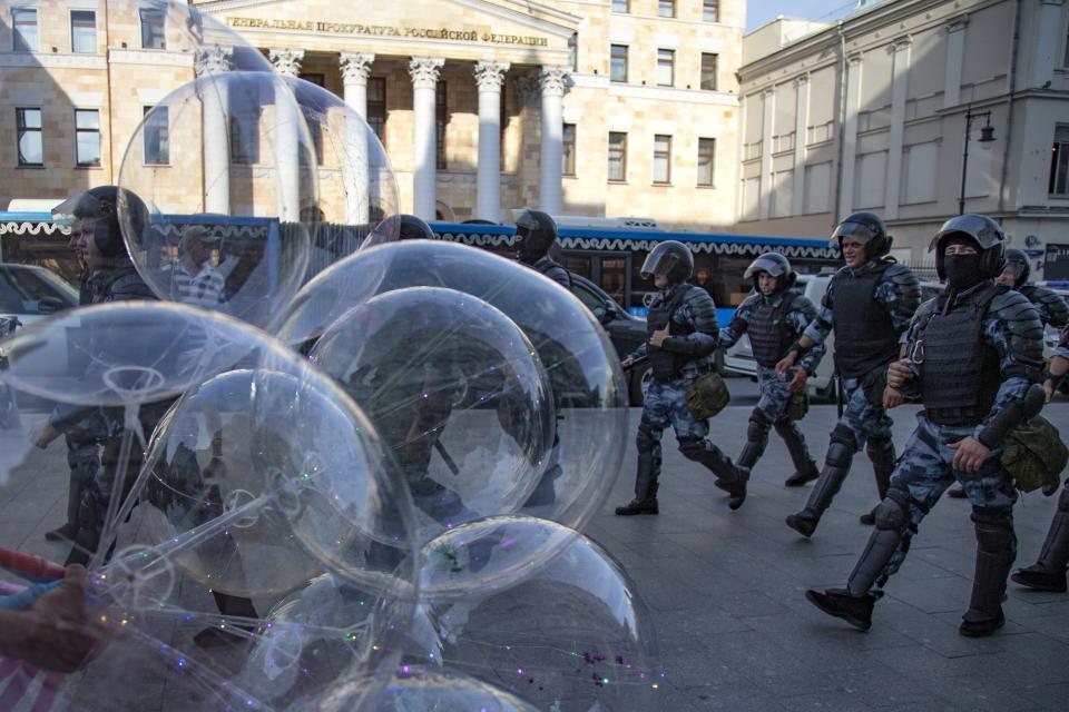 FILE - Police officers walk past a balloon seller as they control a street during an unsanctioned rally in front of the Russian General Prosecution building in Moscow, Saturday, July 27, 2019. The Russian prosecutor general's office has declared The Moscow Times newspaper to be an "undesirable organization." The designation means the newspaper popular with those in Russia's expatriate community must stop any work in Russia. (AP Photo/Alexander Zemlianichenko, File)