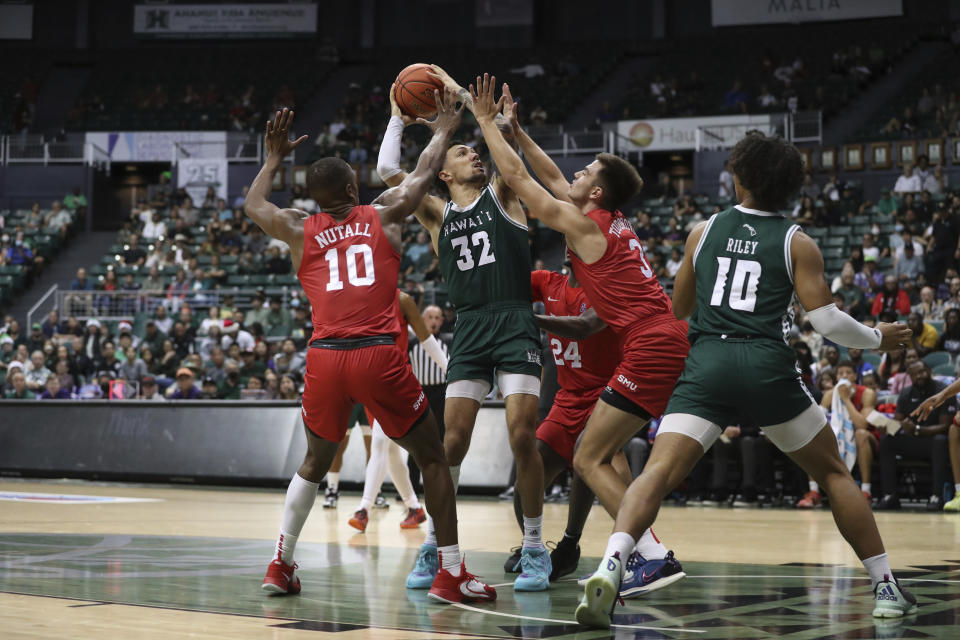 Hawaii guard Samuta Avea (32) tries to shoot between SMU guard Zach Nutall (10) and forward Stefan Todorovic (3) during the first half of an NCAA college basketball game, Sunday, Dec. 25, 2022, in Honolulu. (AP Photo/Marco Garcia)