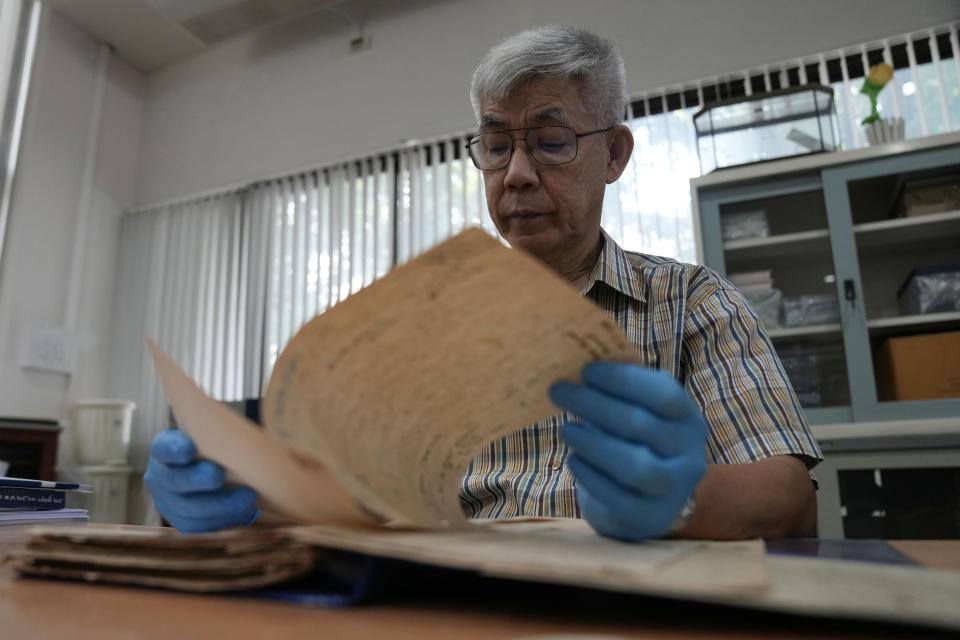 Retired Thai Air Chief Marshal Sakpinit Promthep looks at a WWII-era local Thai police report in the archive room of the Thai Air Force Museum, In Bangkok, Thailand, Friday April 29, 2022. The document helped locate the possible remains of a U.S. pilot, missing from that time, from a crash site in Lampang province. documenting the crash of a U.S. P-38 plane. (AP Photo/Sakchai Lalit)