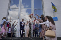 Denys Voznyi and Anna Karpenko leave after getting married in Kyiv, Ukraine, Wednesday, June 15, 2022. A growing number of couples in Ukraine are speedily turning love into matrimony because of the war with Russia. Some are soldiers, marrying just before they head off to fight. Others are united in determination that living and loving to the full are more important than ever in the face of death and destruction. (AP Photo/Natacha Pisarenko)