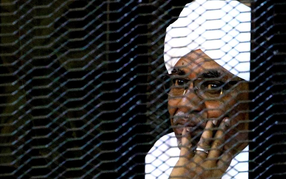 Sudan's former President Omar Hassan al-Bashir sits inside a cage at the courthouse where he is facing corruption charges - REUTERS