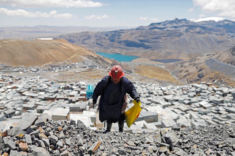 Eva Chura, 42, who is a pallaquera (a female gold picker) strikes rocks that were discarded from a mine in search of gold in the town of La Rinconada, in the Andes