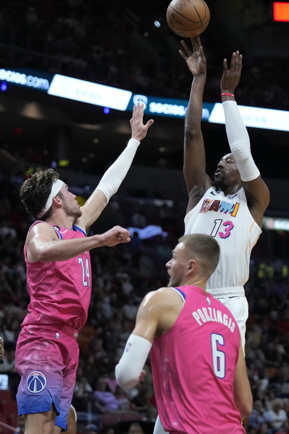 Miami Heat center Bam Adebayo (13) takes a shot against Washington Wizards forward Corey Kispert (24) and center Kristaps Porzingis (6) during the first half of an NBA basketball game, Friday, Nov. 25, 2022, in Miami. (AP Photo/Wilfredo Lee)