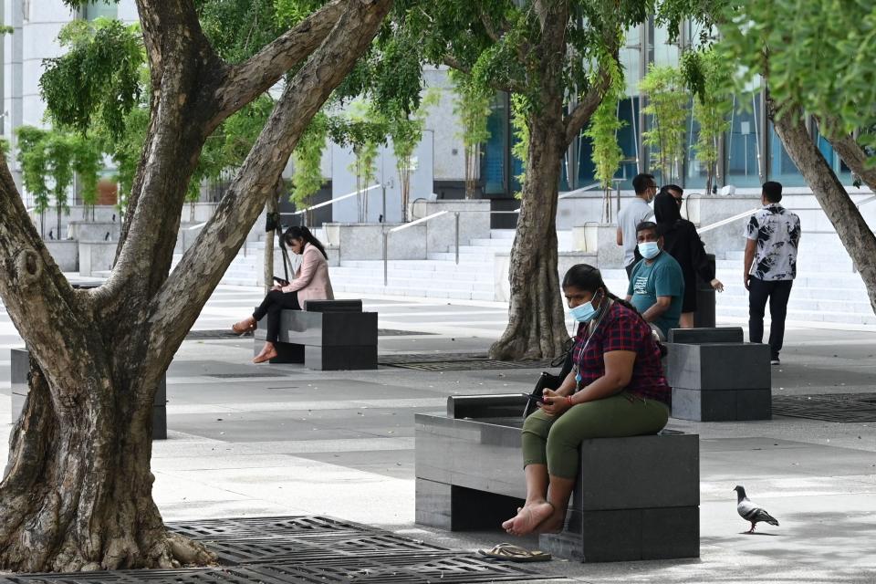 People relax under trees in the financial business district in Singapore on October 21, 2021. / AFP / Roslan RAHMAN