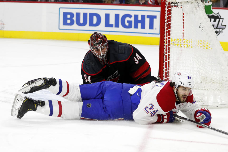 Montreal Canadiens' Phillip Danault (24) slides on the ice past Carolina Hurricanes goaltender Petr Mrazek (34), of the Czech Republic, during the first period of an NHL hockey game in Raleigh, N.C., Tuesday, Dec. 31, 2019. (AP Photo/Karl B DeBlaker)
