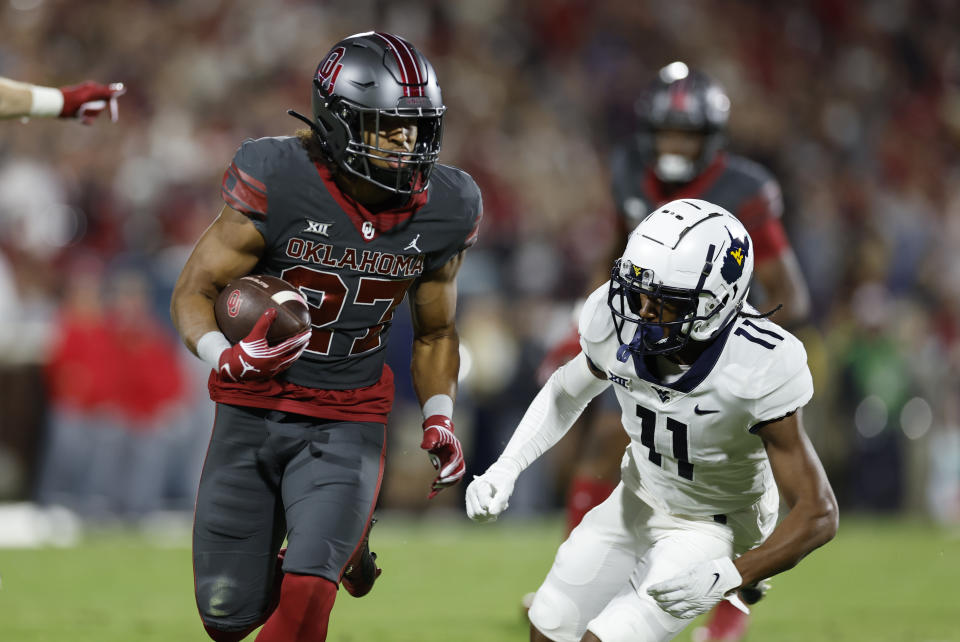 Oklahoma running back Gavin Sawchuk (27) runs ahead of West Virginia cornerback Beanie Bishop Jr. (11) for a first down during the first half of an NCAA college football game Saturday, Nov. 11, 2023, in Norman, Okla. (AP Photo/Alonzo Adams)