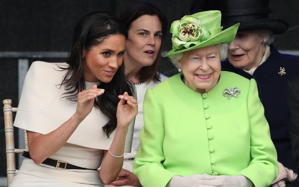 The Duchess of Sussex and the late Queen look amused together, with Samantha Cohen behind them