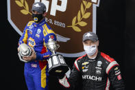 Josef Newgarden holds the trophy after winning an IndyCar auto race at Indianapolis Motor Speedway in Indianapolis, Friday, Oct. 2, 2020. Alexander Rossi, left, finished second. (AP Photo/Michael Conroy)