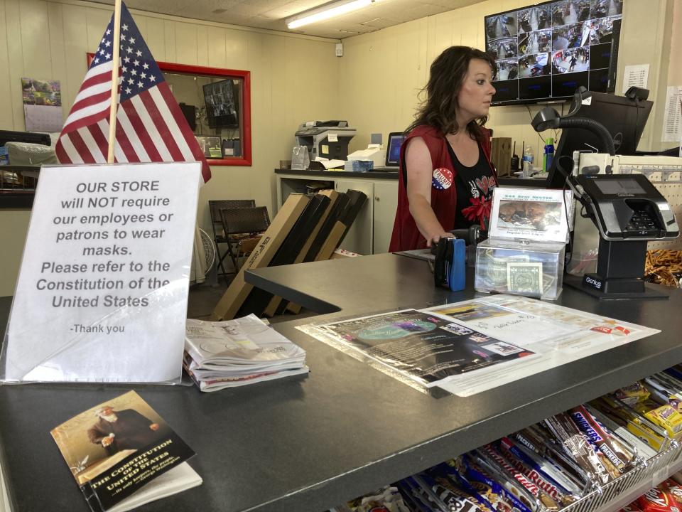Melissa Laperuta wears a campaign button for President Trump at her family's hardware store on May 13, 2021, in Alamogordo, N.M., where defiance of state pandemic health orders has been on prominent display. A recall effort is underway in Alamogordo and surrounding Otero County against County Commissioner Couy Griffin, who founded the support group Cowboys for Trump and held horseback caravas across the country starting in 2019. Griffin is reviled and revered as he confronts criminal charges for joining protests on the steps of the U.S. Capitol on Jan. 6. and state probes into his finances. (AP Photo/Morgan Lee)