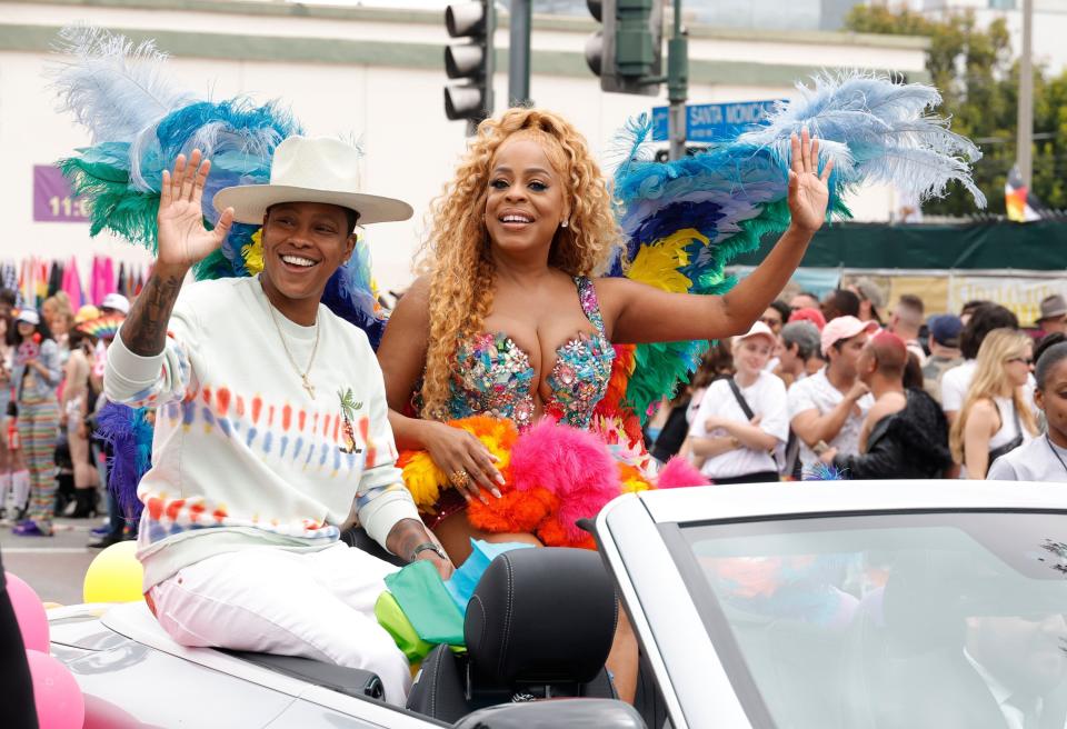 Jessica and Niecy Nash-Betts sitting on the back of a convertible and waving to the crowd