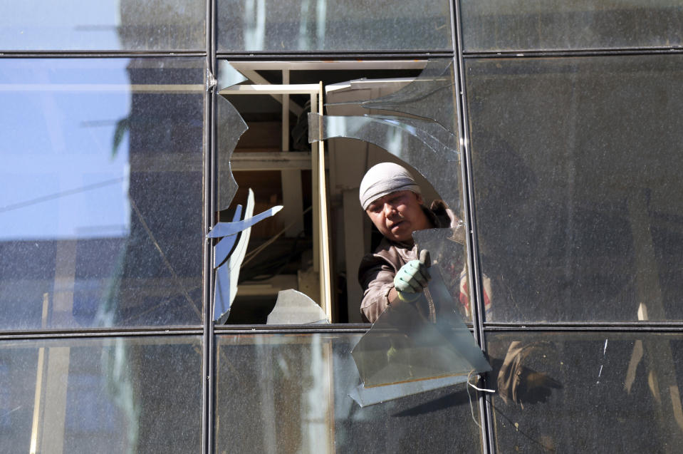 An Afghan worker removes the shuttered glasses of a shop near the site of Wednesday's attack in Kabul, Afghanistan, Thursday, May 9, 2019. Taliban fighters attacked the offices of a U.S.-based aid organization in the Afghan capital on Wednesday, setting off a huge explosion and battling security forces in an assault, the Interior Ministry said. (AP Photo/Rahmat Gul)