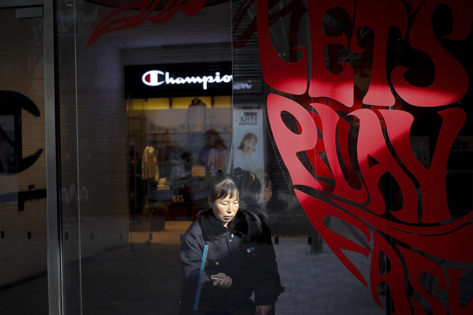 A cleaner wipes window panels near a shop of American sportswear brand Champion, at the capital city's popular shopping mall in Beijing, Wednesday, Feb. 13, 2019. U.S. and Chinese negotiators are meeting this week for their final trade talks before U.S. President Donald Trump decides whether to escalate a dispute over technology with a March 2 tariff hike on $200 billion of imports from China. (AP Photo/Andy Wong)