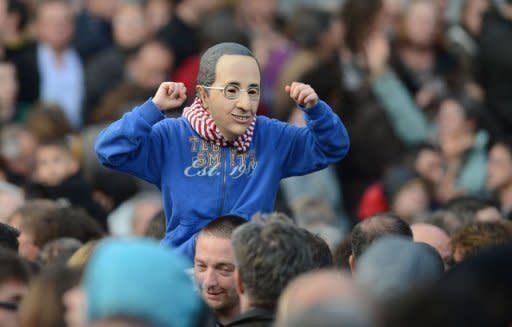 A boy wearing a mask representing Socialist Party (PS) candidate for the 2012 French presidential election Francois Hollande listens to a speech given after the results of the second round of the presidential election in Tulle, southwestern France