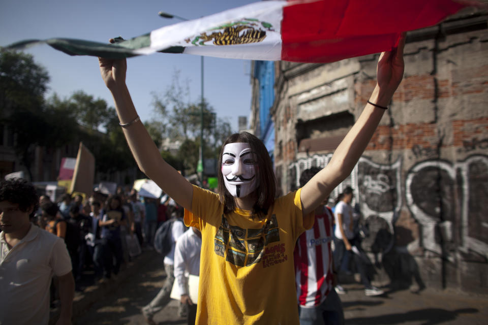 FILE - In this May 28, 2012 file photo, a demonstrator holds up Mexico's national flag during a protest against a possible return of the old ruling Institutional Revolutionary Party (PRI) in Mexico City. Students challenged presidential candidates to debates, urged others their age to pay attention to the campaign, and sought to fight off the return of the Institutional Revolutionary Party, which held power for 71 years until its ouster in 2000. Mexico will hold presidential elections on July 1. (AP Photo/Alexandre Meneghini, file)