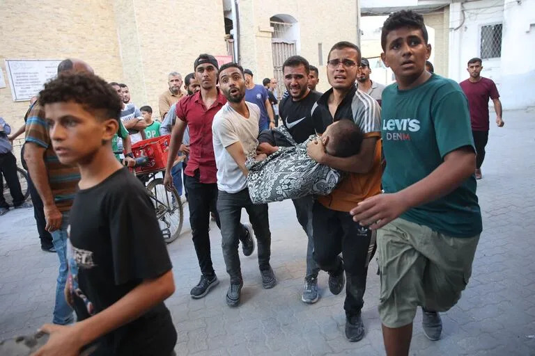 TOPSHOT - Varias personas llevan a una víctima a un hospital tras un ataque israelí contra una escuela en el distrito de Zeitoun, a las afueras de la ciudad de Gaza, el 1 de septiembre de 2024, en medio del conflicto entre Israel y el grupo palestino Hamas.