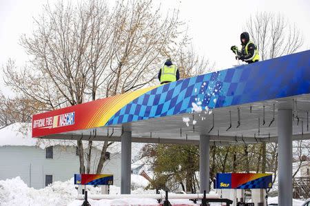 Workers remove snow from the roof of a gas station in the City of Lackawanna, New York, November 22, 2014. REUTERS/Aaron Ingrao