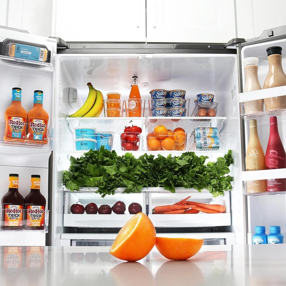 Clear fridge organizer bins with produce on fridge shelves