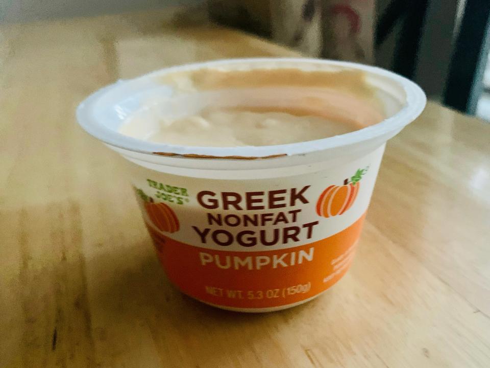 the orange and white container of Trader Joe's pumpkin Greek yogurt on wooden table