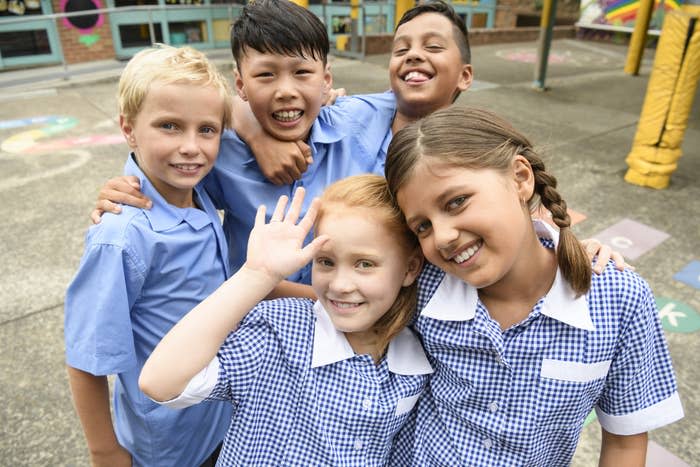 A group of five schoolchildren pose in their uniforms for the camera