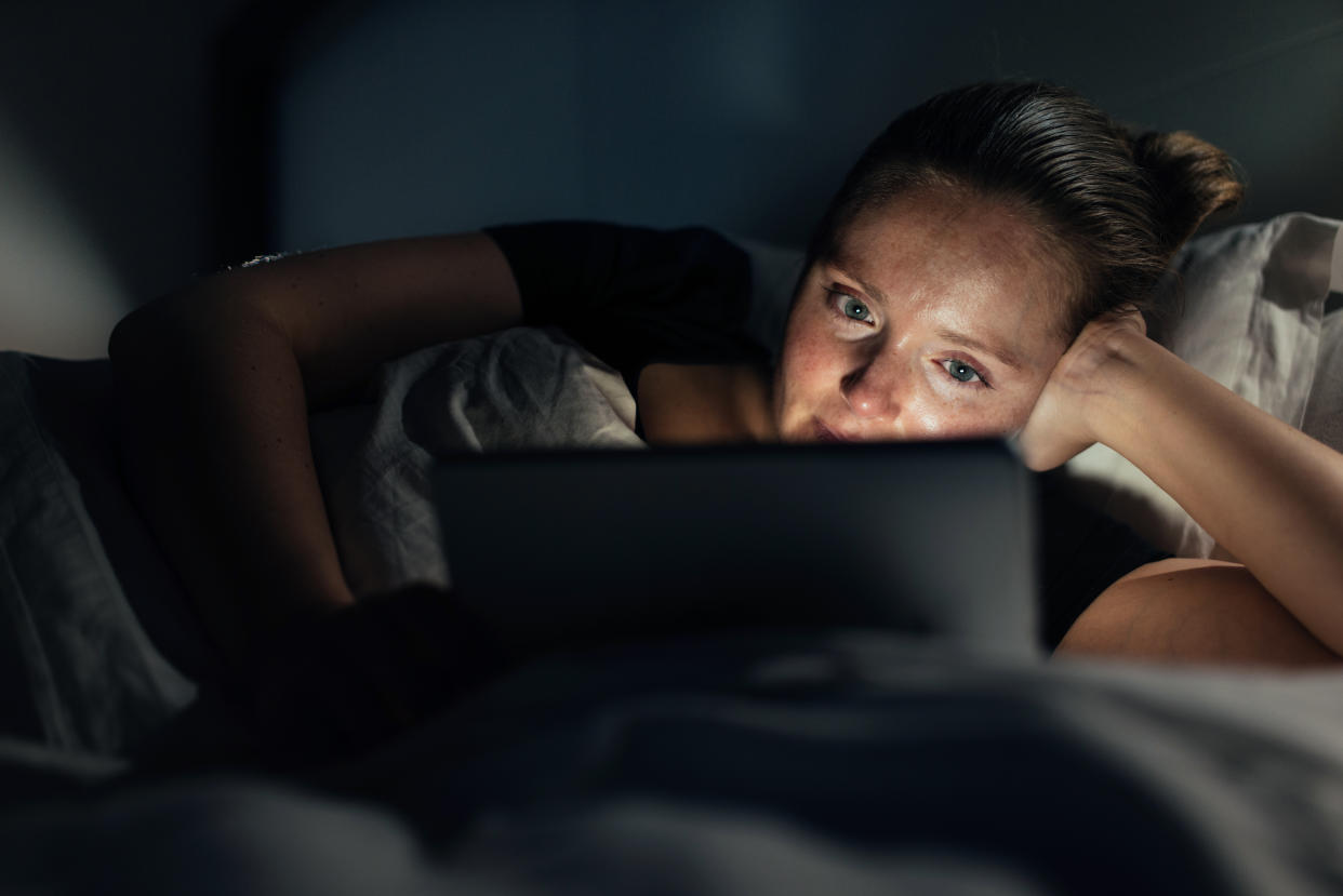 Frau benutzt ein Tablet mitten in der Nacht im Bett