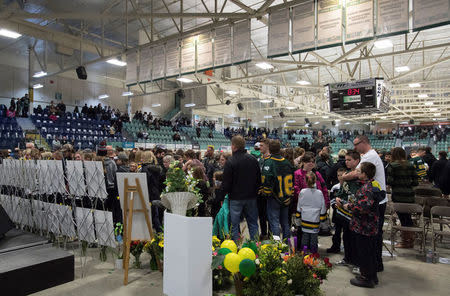 People look at photos of the victims during a vigil at the Elgar Petersen Arena, home of the Humboldt Broncos, to honour the victims of a fatal bus accident in Humboldt, Saskatchewan, Canada April 8, 2018. Jonathan Hayward/Pool via REUTERS