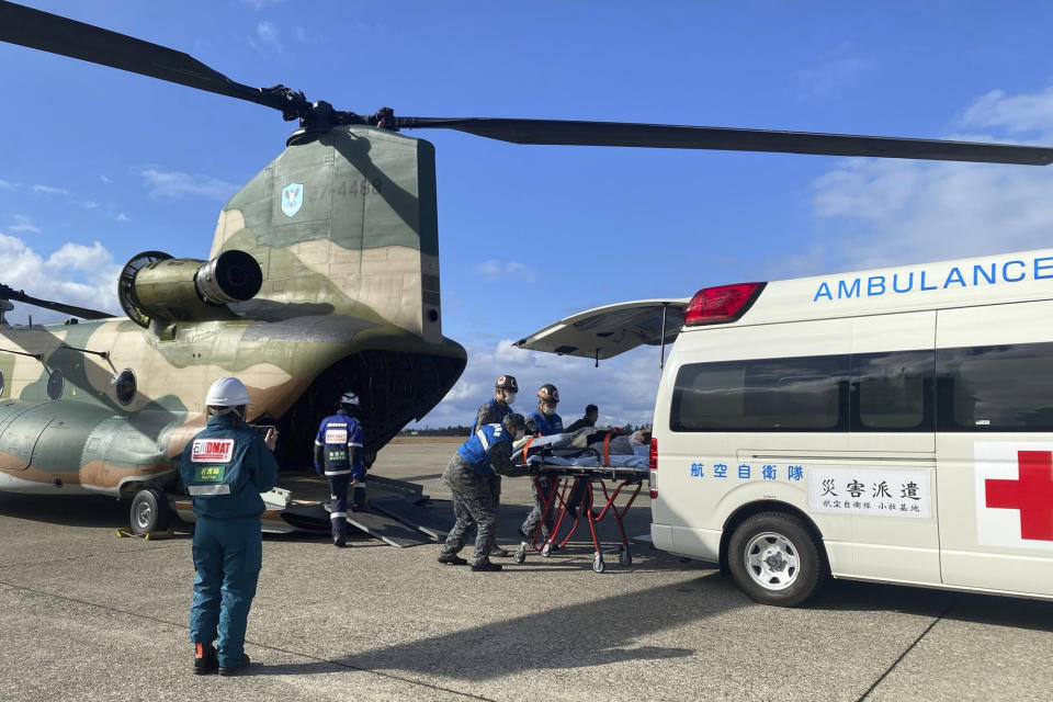 In this photo provided by Japanese Ministry of Defense, members of Japan Self-Defense Forces carry an injured person from the quake-hit area, to an ambulance at Komatsu base, Ishikawa prefecture, Japan Monday, Jan. 8, 2024. (Japanese Ministry of Defense via AP)