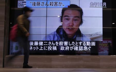 A pedestrian walks past television screens displaying a news program about Japanese journalist Kenji Goto, who was held hostage by Islamic State militants, on a street in Tokyo February 1, 2015. REUTERS/Yuya Shino