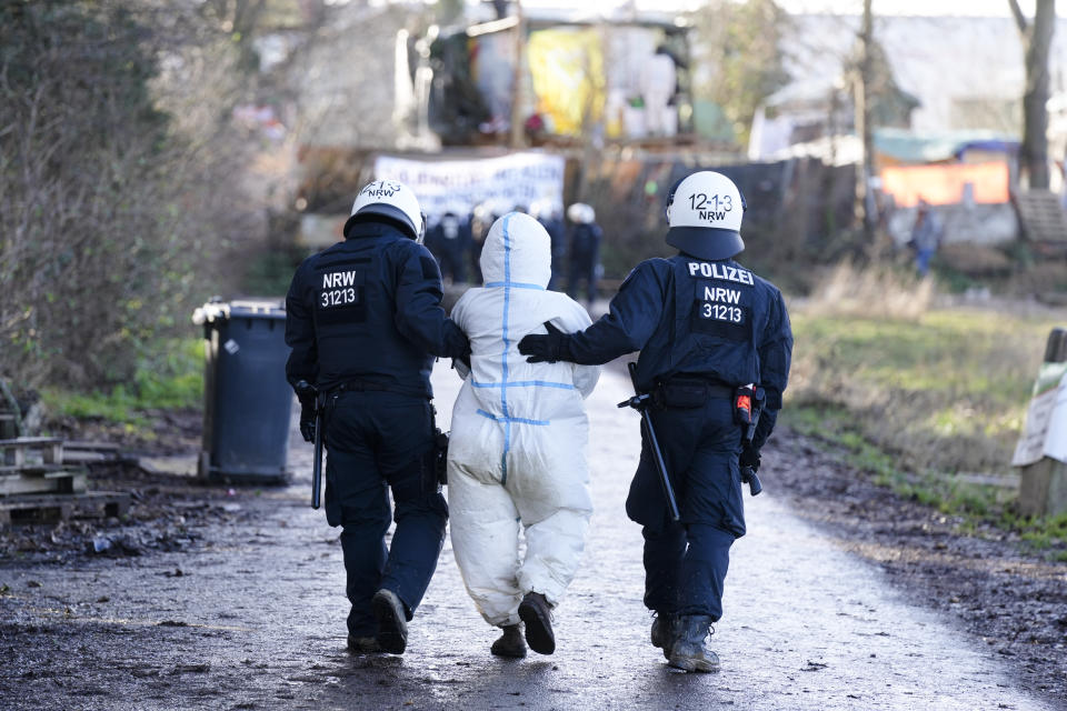 Police officers lead away a protestor at the village Luetzerath, near Erkelenz, Germany, Wednesday, Jan. 11, 2023. Police have entered the condemned village in, launching an effort to evict activists holed up at the site in an effort to prevent its demolition to make way for the expansion of a coal mine. (AP Photo/Michael Probst)