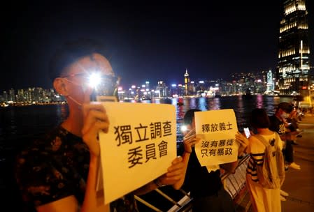 Protesters hold placards as they form a human chain during a rally to call for political reforms along Tsim Sha Tsui and Hung Hom Promenade in Hong Kong