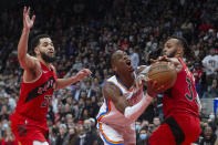 Oklahoma City Thunder's Shai Gilgeous-Alexander, center, drives to the basket between Toronto Raptors' Gary Trent Jr., right, and Fred VanVleet during the second half of an NBA basketball game Wednesday, Dec. 8, 2021, in Toronto. (Chris Young/The Canadian Press via AP)