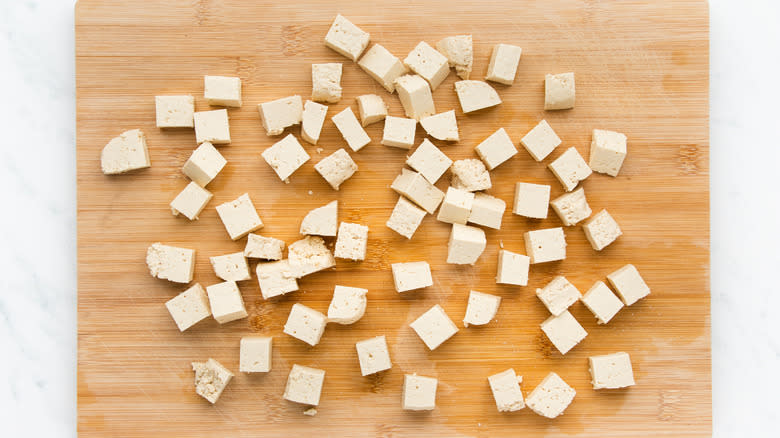 Diced tofu on wooden chopping board