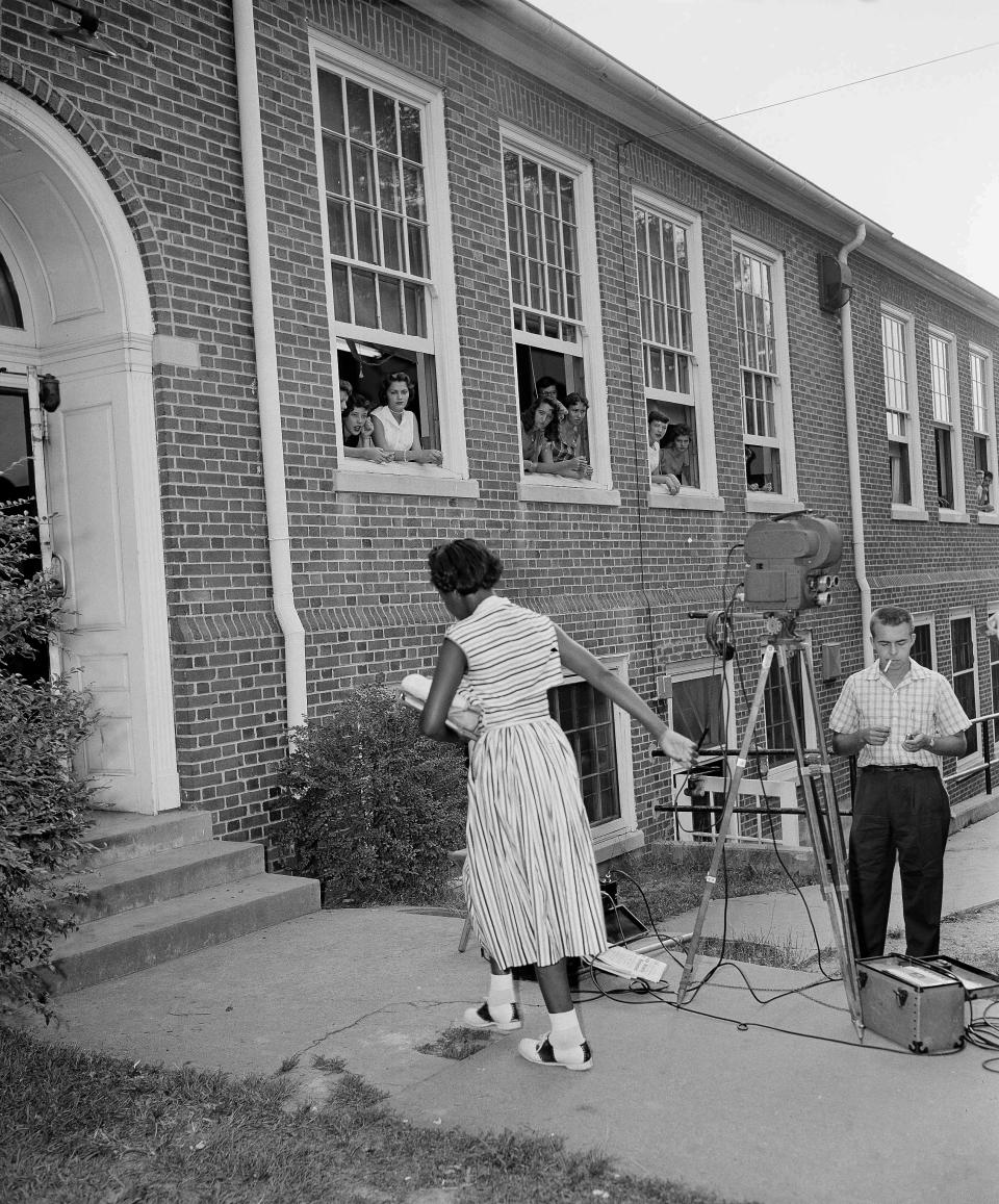 Theresser Caswell, 13, of Claxton, Tenn., one of 12 African-American pupils attending the newly integrated Clinton High School, walks to the front entrance as fellow schoolmates peer out of windows, in Clinton, Tenn., Sept. 5, 1956. A newsreel cameraman is at right. Gene Herrick, a retired Associated Press photographer who covered the Korean War and is known for his iconic images of Martin Luther King Jr., Rosa Parks and the civil rights movement, died Friday, April 12, 2024 at a nursing home in Rich Creek, Virginia. He was 97. (AP Photo/Gene Herrick)