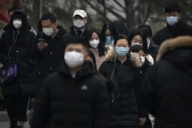 Transeúntes con mascarilla caminan por una calle de un distrito empresaria en el centro de Pekín, China, el 12 de enero de 2023. (AP Foto/Mark Schiefelbein)