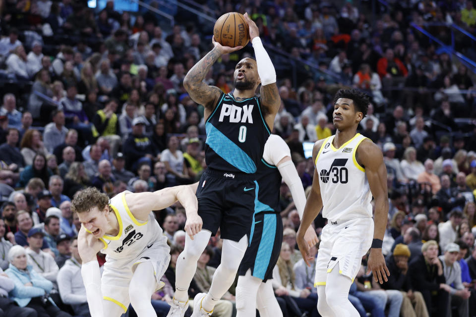 Portland Trail Blazers guard Damian Lillard (0) shoots against the Utah Jazz forward Lauri Markkanen (23), left, and guard Ochai Agbaji (30) in the first half during an NBA basketball game, Wednesday, March 22, 2023, in Salt Lake City. (AP Photo/Jeff Swinger)