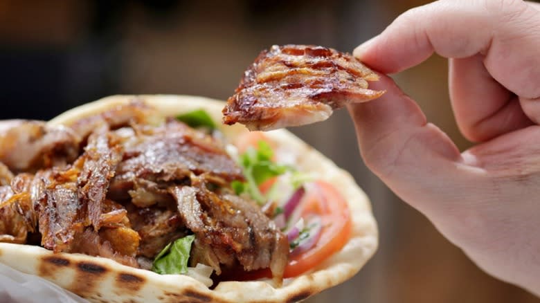 hand plucking meat from gyro