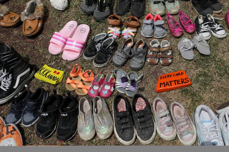 Children's shoes line the base of the defaced statue of Egerton Ryerson in Toronto