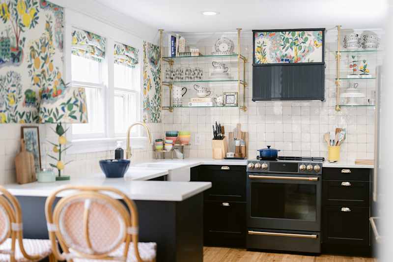 Glass open shelves in newly renovated kitchen with black cabinets.