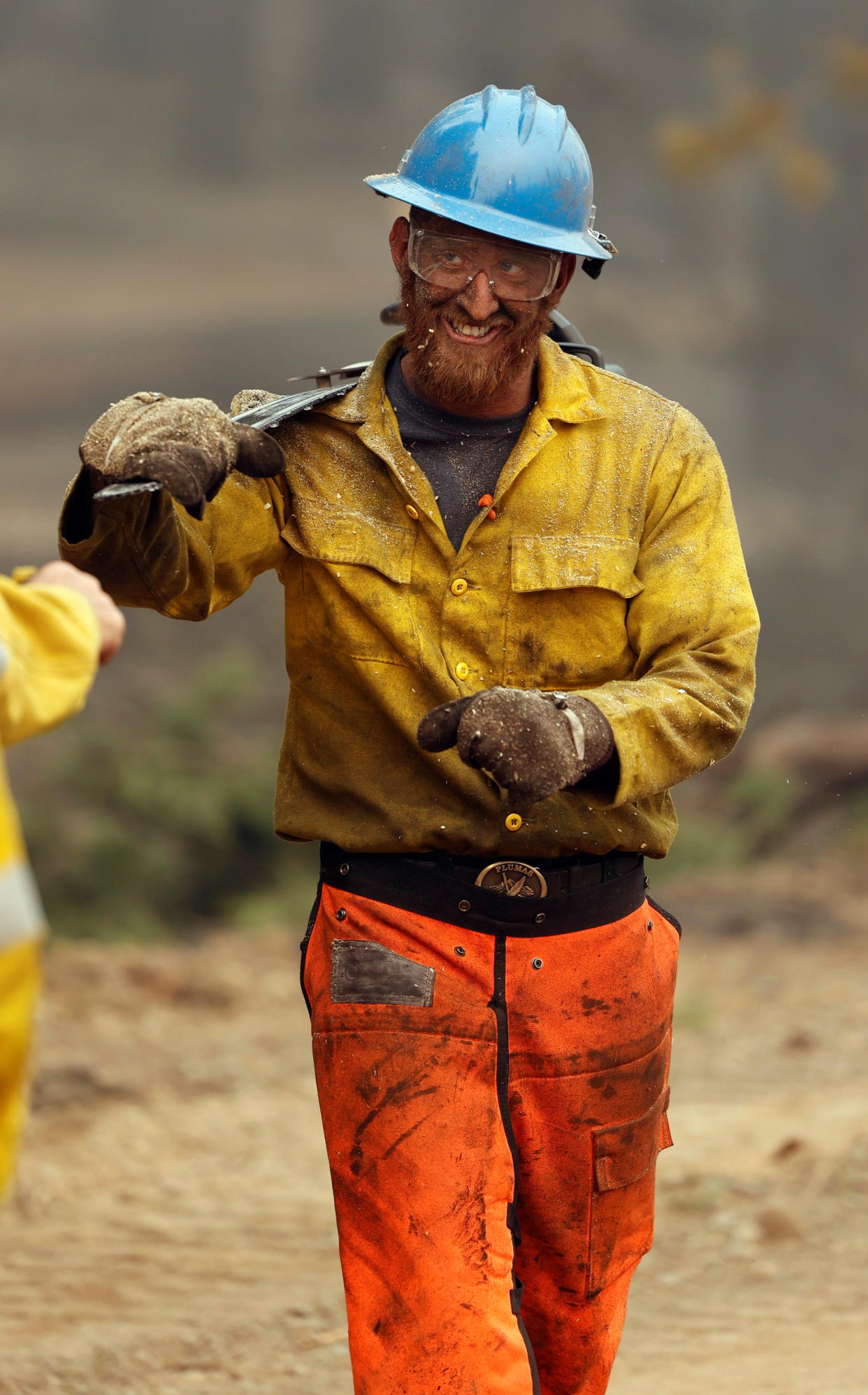 Contract feller and firefighter with Sierra Nevada Timber, David Coffey, smiles as he walks away from a burning trees he cut down at the Dixie Fire near Chester, California, U.S. August 7, 2021. REUTERS/Fred Greaves