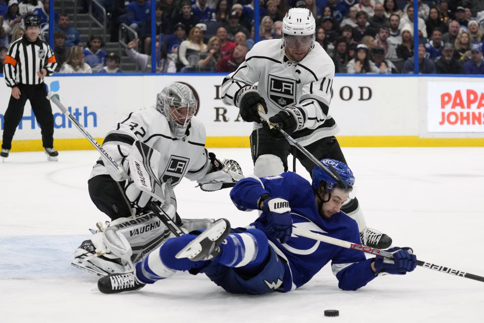 Tampa Bay Lightning center Anthony Cirelli (71) tries to play the puck after getting knocked down by Los Angeles Kings center Anze Kopitar (11) in front of goaltender Jonathan Quick (32) during the second period of an NHL hockey game Saturday, Jan. 28, 2023, in Tampa, Fla. (AP Photo/Chris O'Meara)