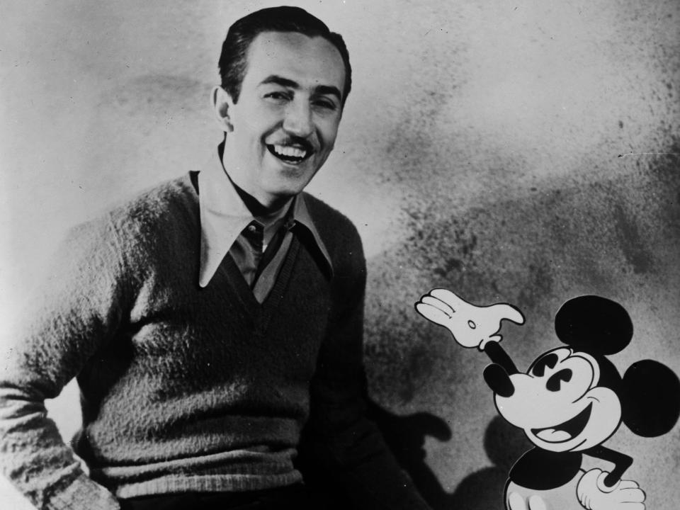 Walt Disney sitting next to an and animated Mickey Mouse.