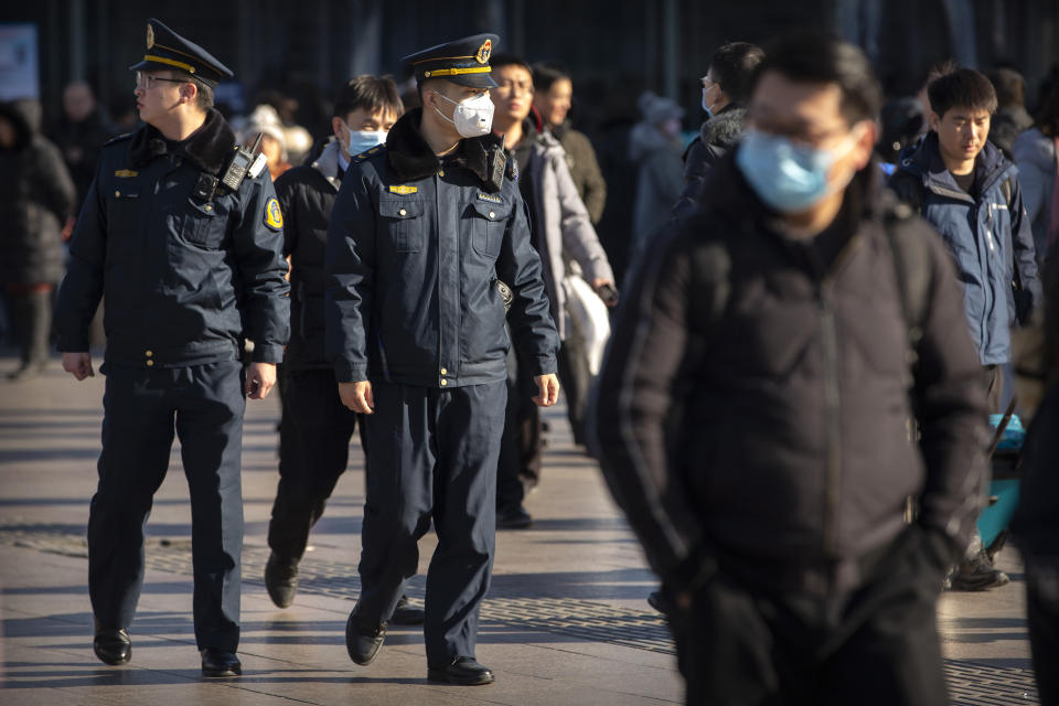 Un agente de seguridad utiliza un cubrebocas mientras vigila afuera de la estación de trenes en Beijing el lunes 20 de enero de 2020. (AP Foto/Mark Schiefelbein)