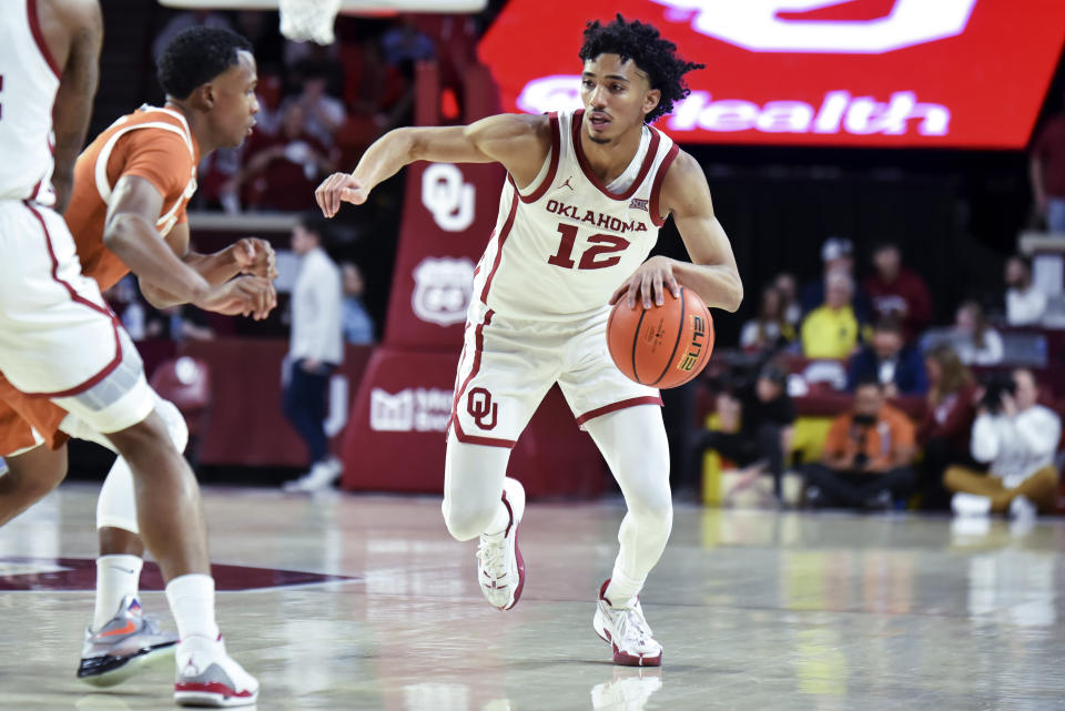 Oklahoma guard Milos Uzan, right, drives past Texas guard Max Abmas during the first half of an NCAA college basketball game Tuesday, Jan. 23, 2024, in Norman, Okla. (AP Photo/Kyle Phillips)